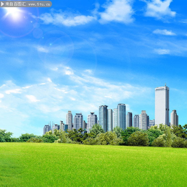 蓝天白云下草地和城市建筑背景图片
