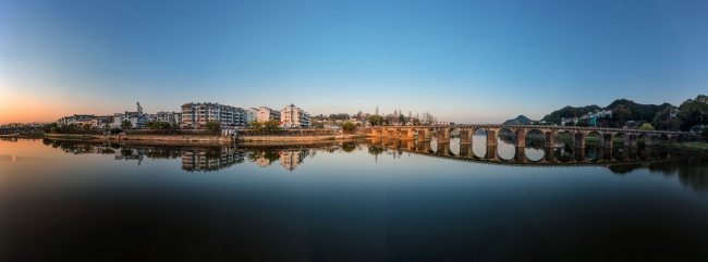 宽幅日落时分倒影水中的古城古桥全景风景图片