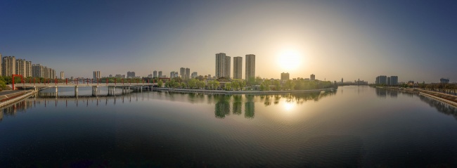 宽幅日出时分静谧水面倒映城市天际城市摄影