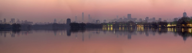 朝霞映衬下湖光倒影下的城市剪影图片